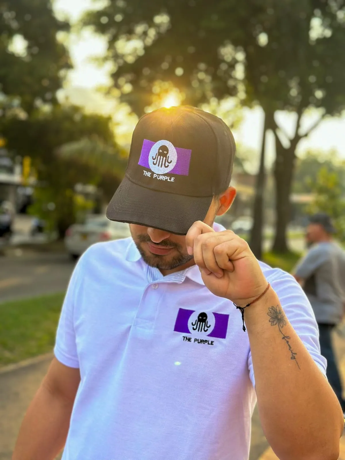 Hombre con camiseta tipo polo blanca y gorra negra bordadas