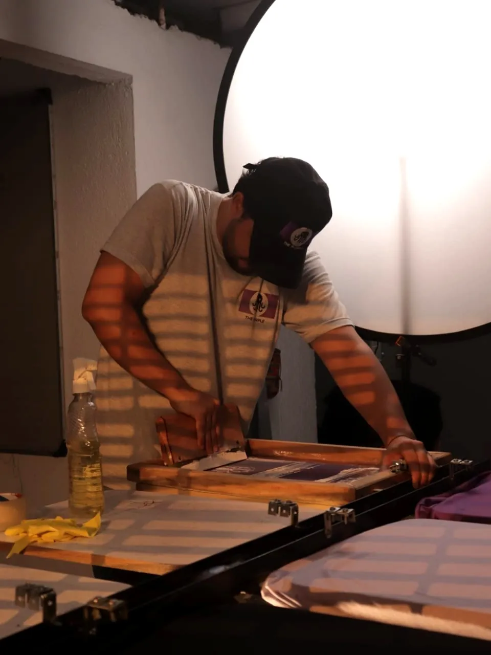 Integrante del taller estampando en serigrafía con racleta sobre el marco